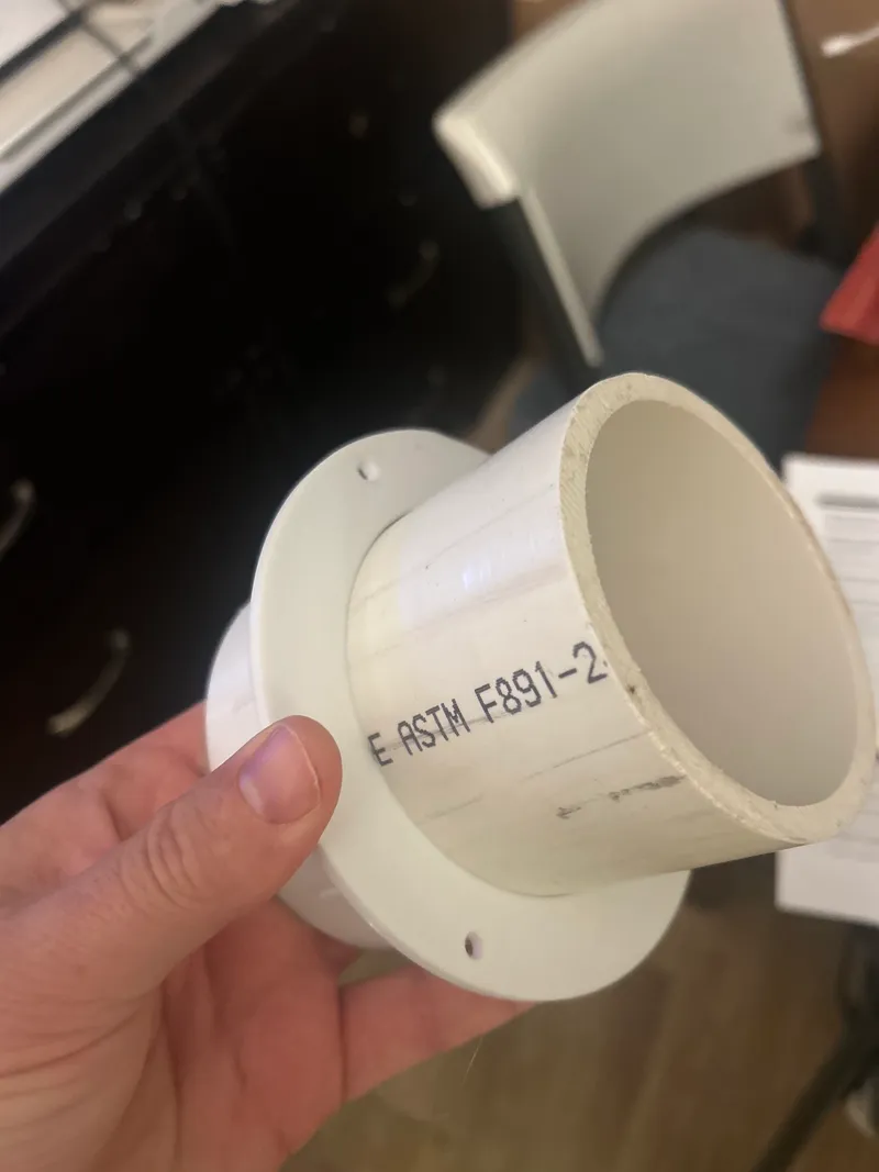 3D printed round-pipe-to-downspout adapter held in hand, fitted over ASTM PVC pipe