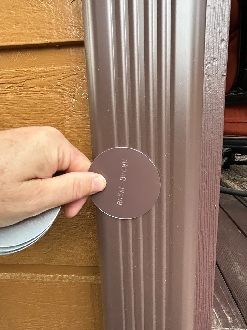 Checking a Royal Brown manufacturer color swatch against the installed downspout